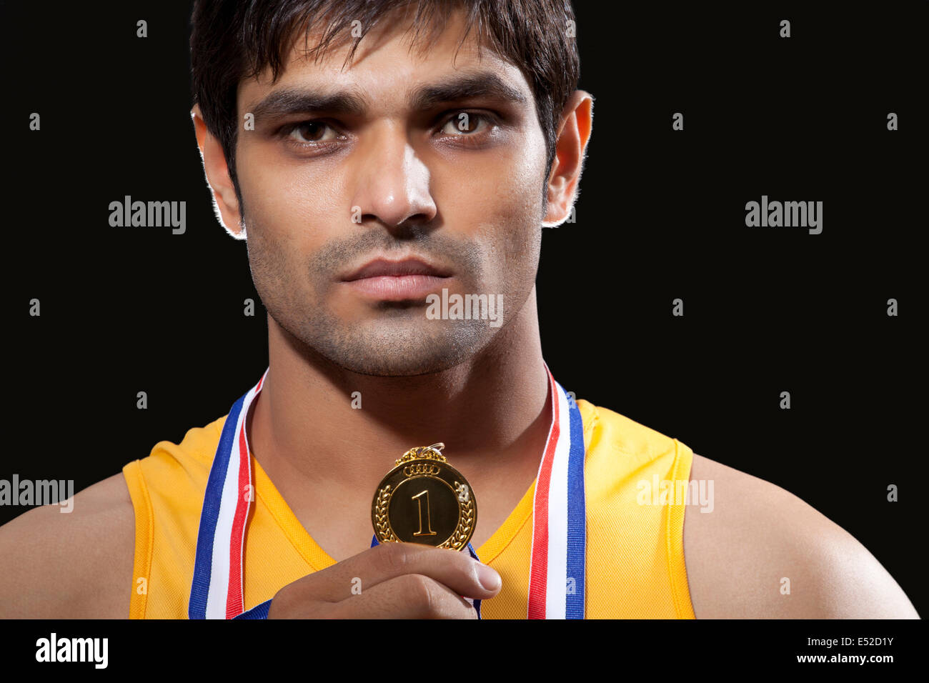 Close-up portrait of young male runner holding médaille d'isolé sur fond noir Banque D'Images