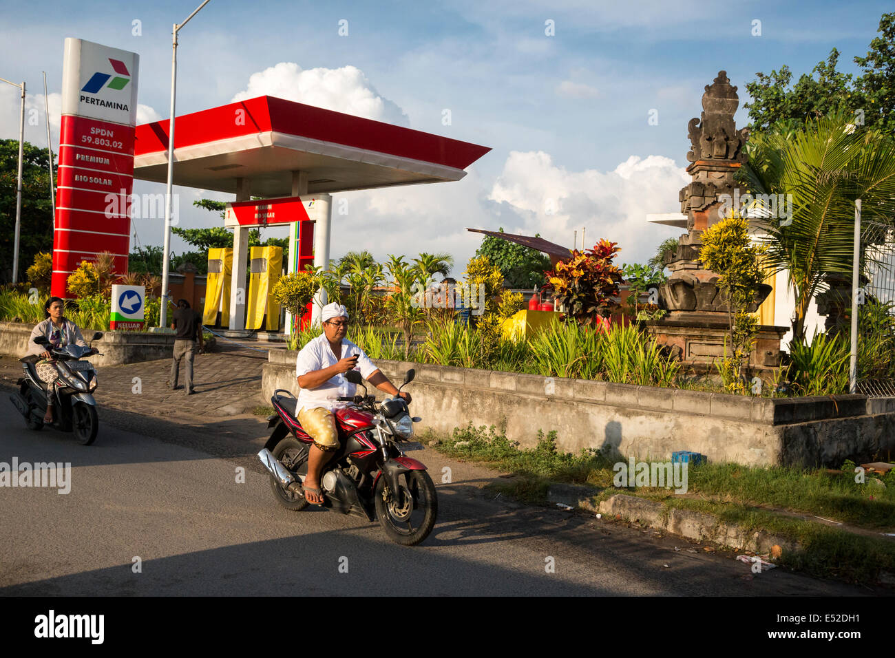 Bali, Indonésie. Man Checking Cell Phone comme il conduit moto avec une main. Pas de casque. Banque D'Images