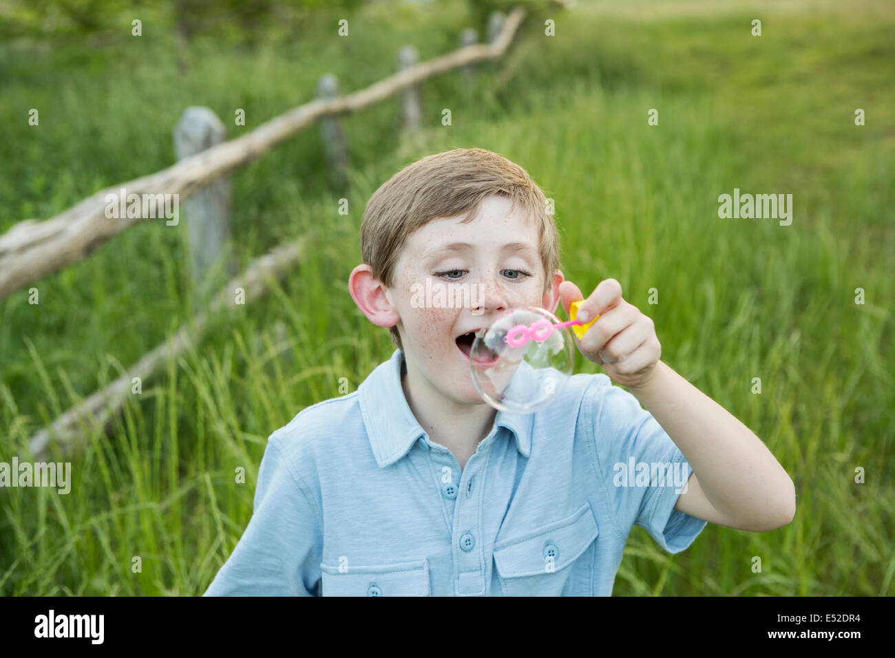 Un garçon dans une chemise bleue, faisant des bulles. Banque D'Images