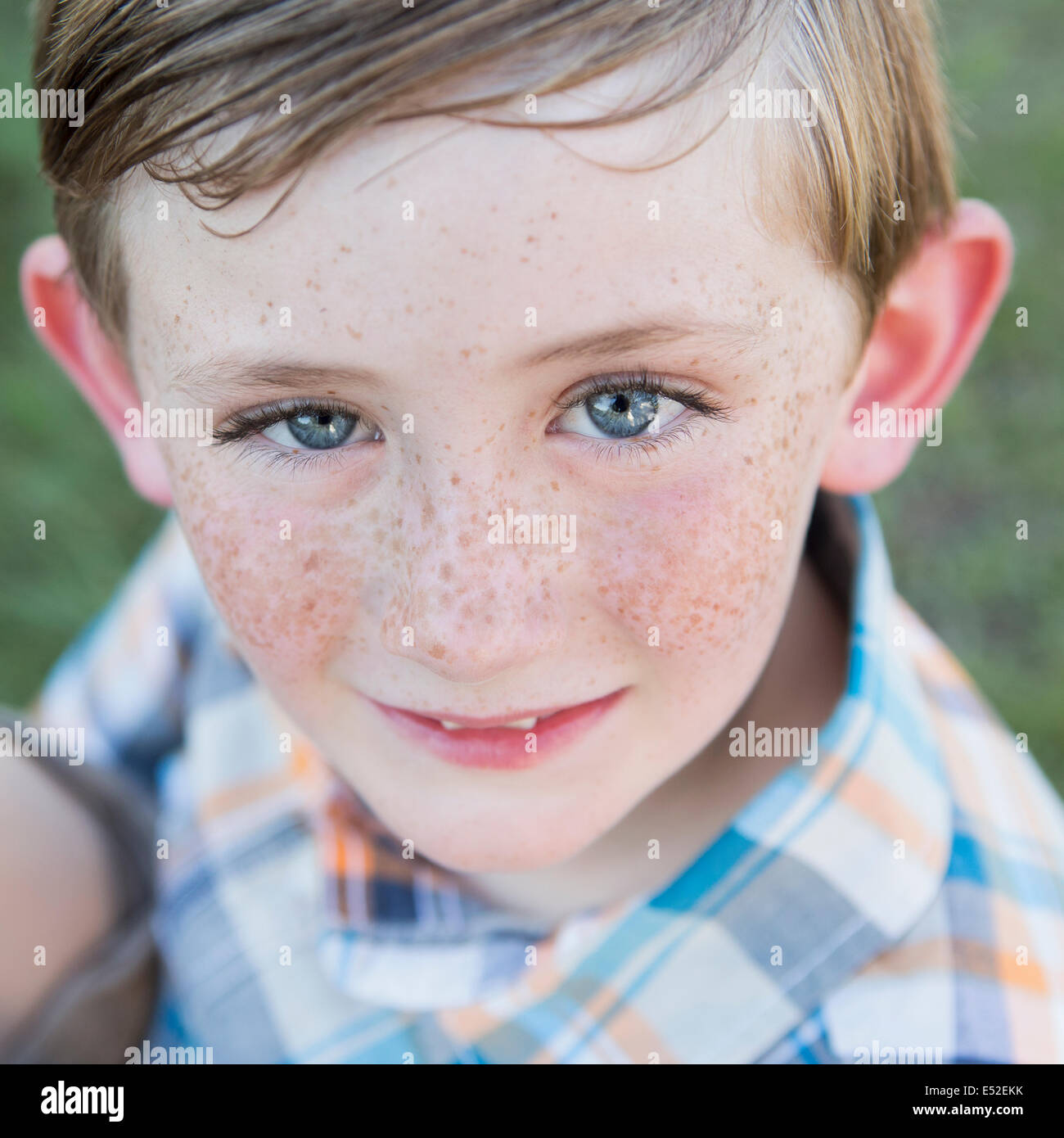 Portrait d'un jeune garçon avec des yeux bleus et des taches de rousseur sur son nez. Banque D'Images