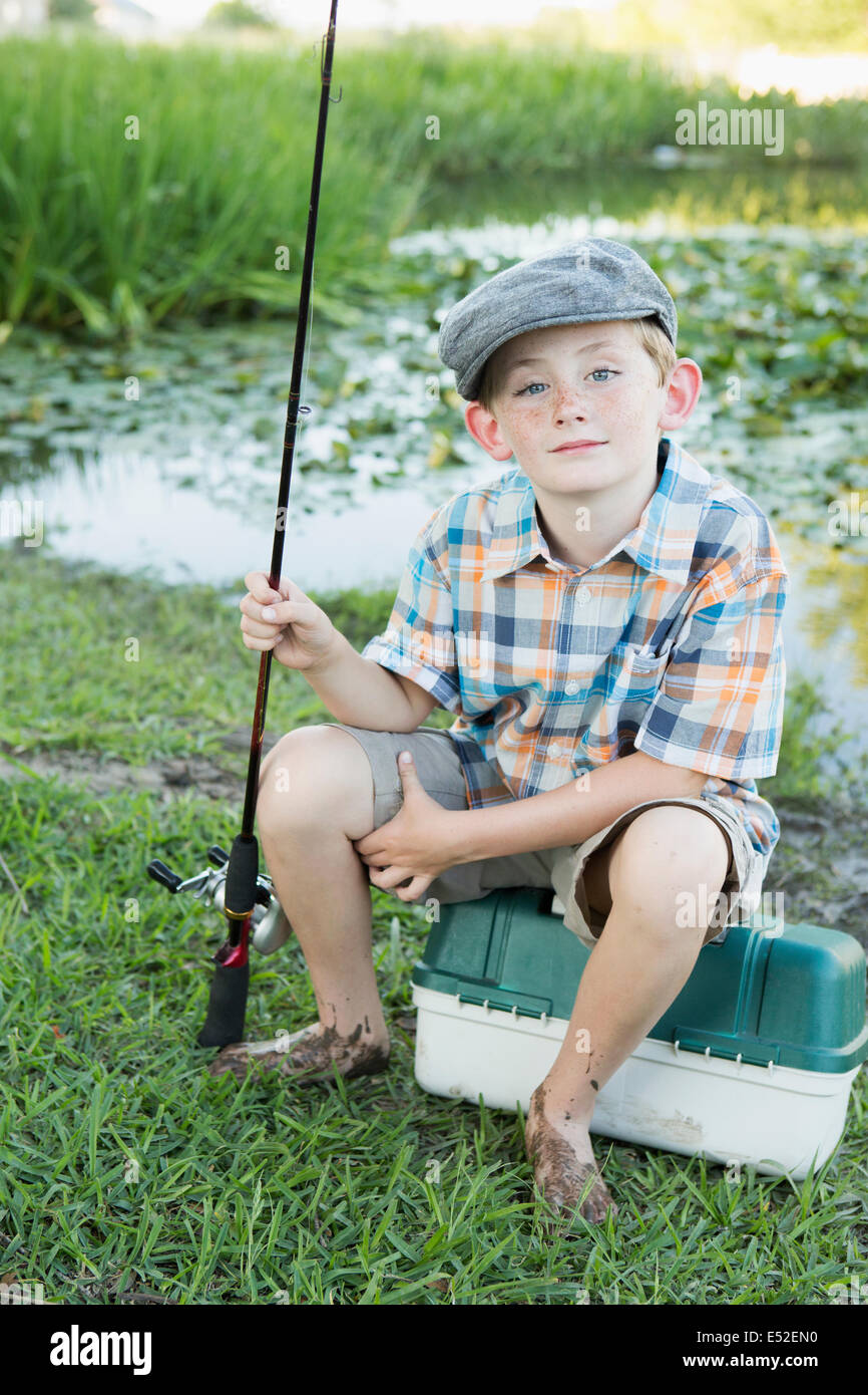 Un jeune garçon avec sa pêche à la route, par un lac ou rivière. Banque D'Images