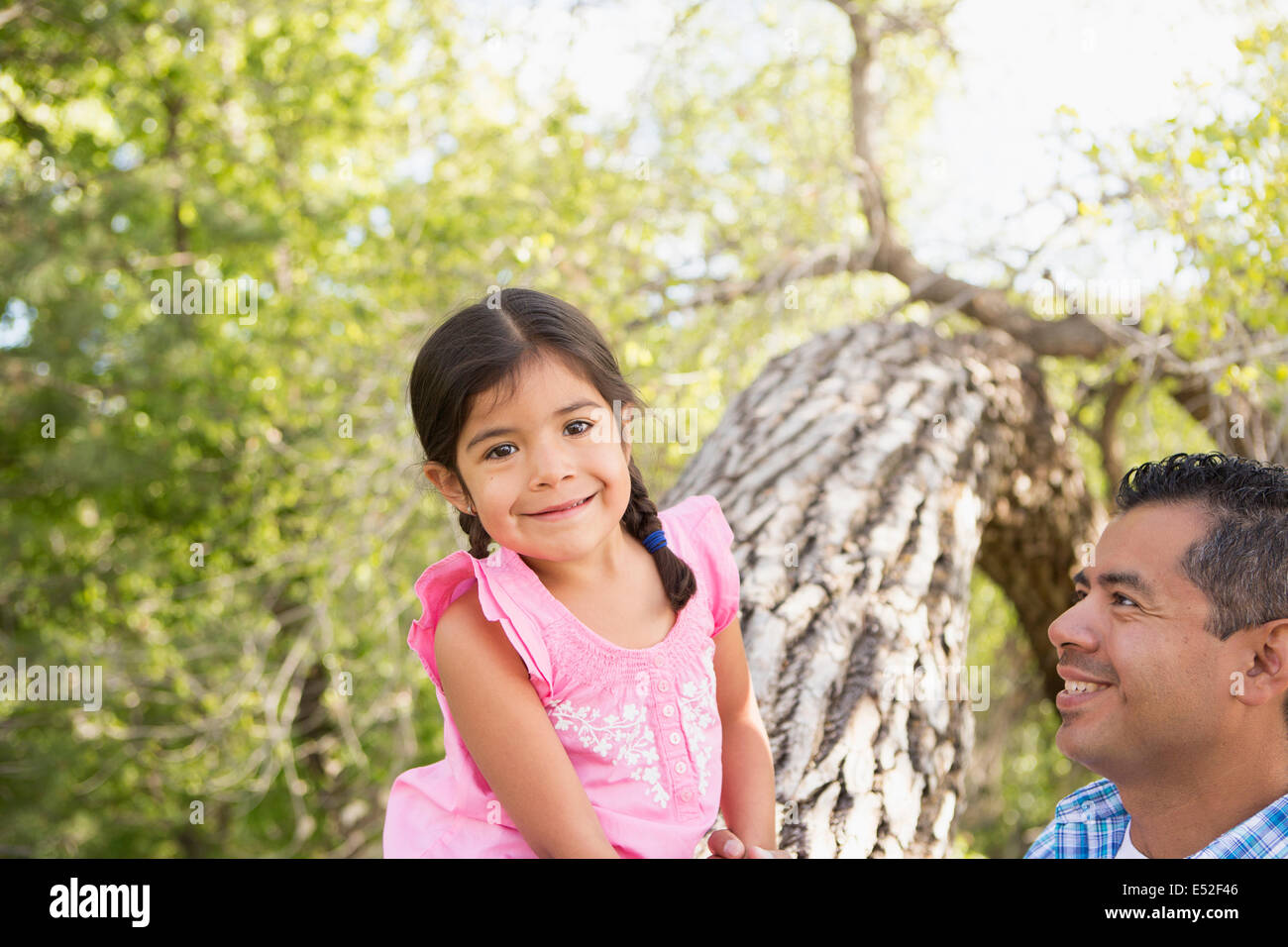 Une jeune fille assise sur un tronc d'arbre à côté de son père. Banque D'Images