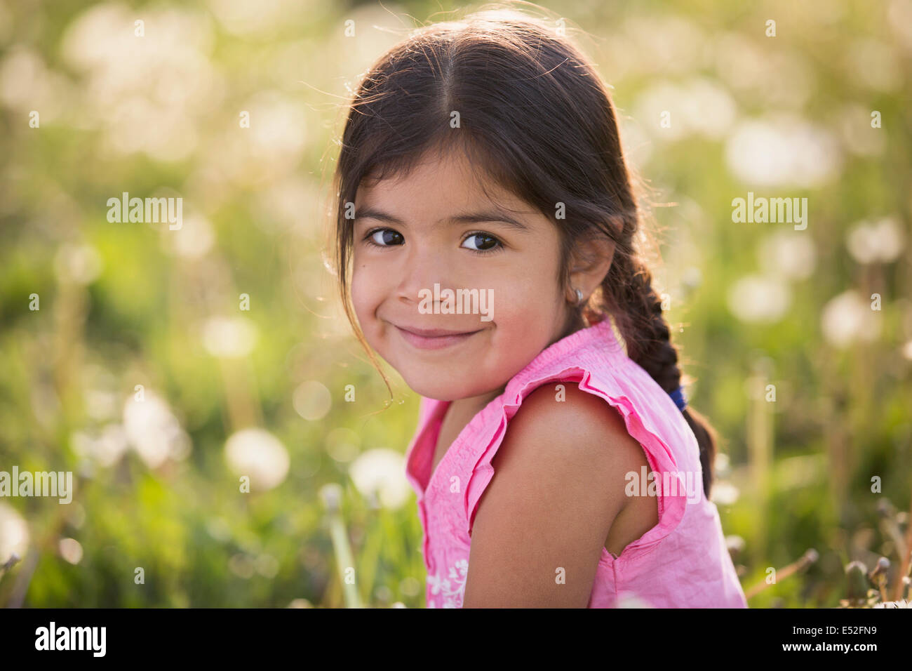 Une jeune fille aux cheveux bruns et tresses, dans une prairie de fleurs sauvages. Banque D'Images