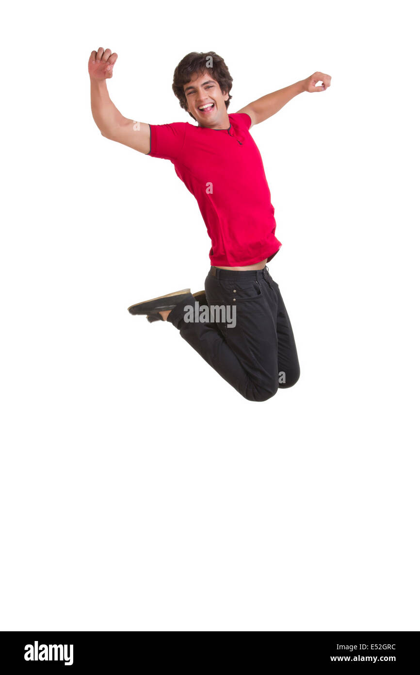 Toute la longueur de l'heureux jeune homme jumping with arms raised over white background Banque D'Images