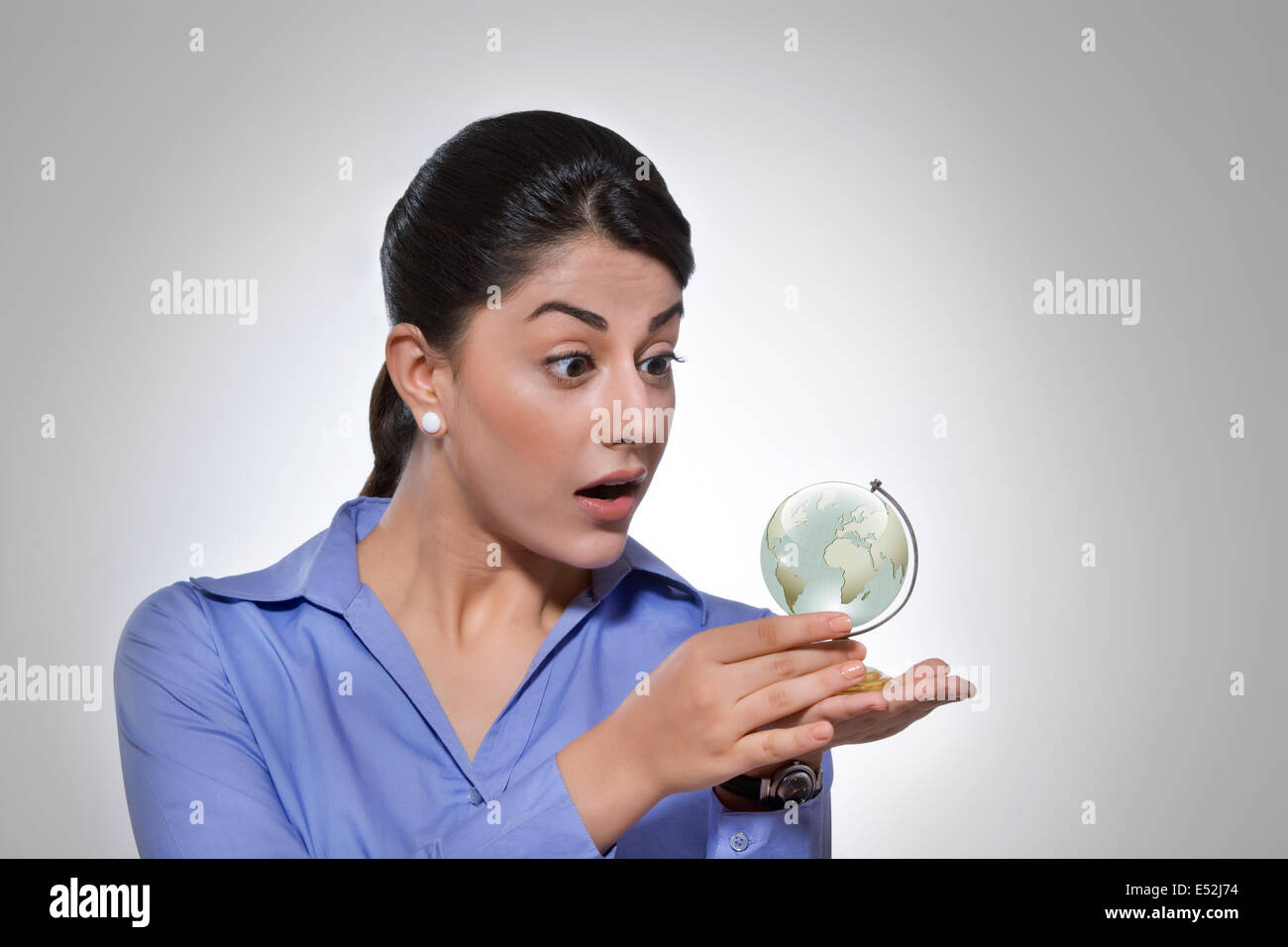 Surpris businesswoman looking at globe de cristal sur fond gris Banque D'Images