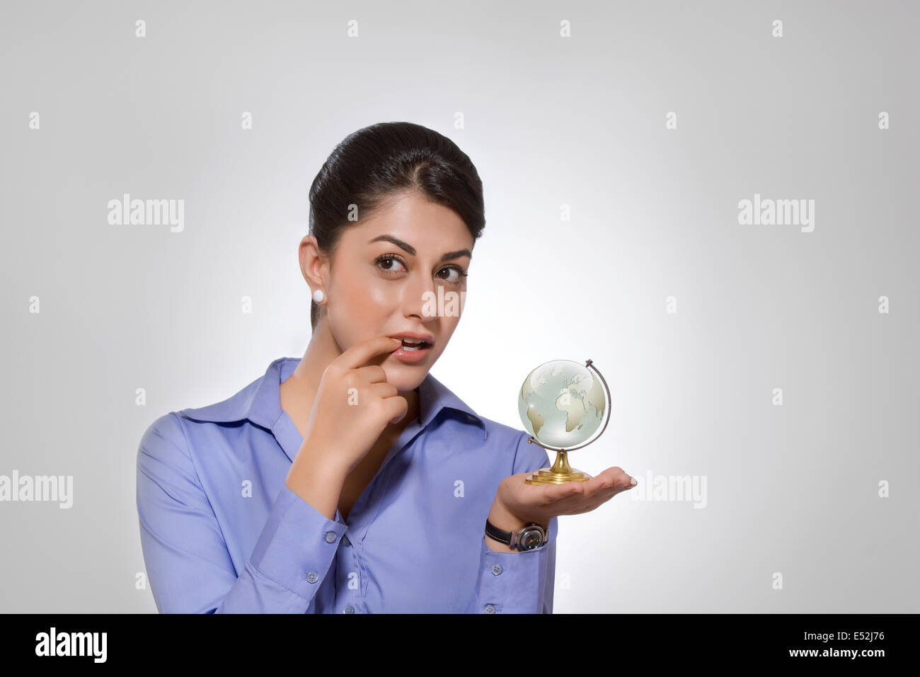 Thoughtful Indian businesswoman holding globe sur fond gris Banque D'Images