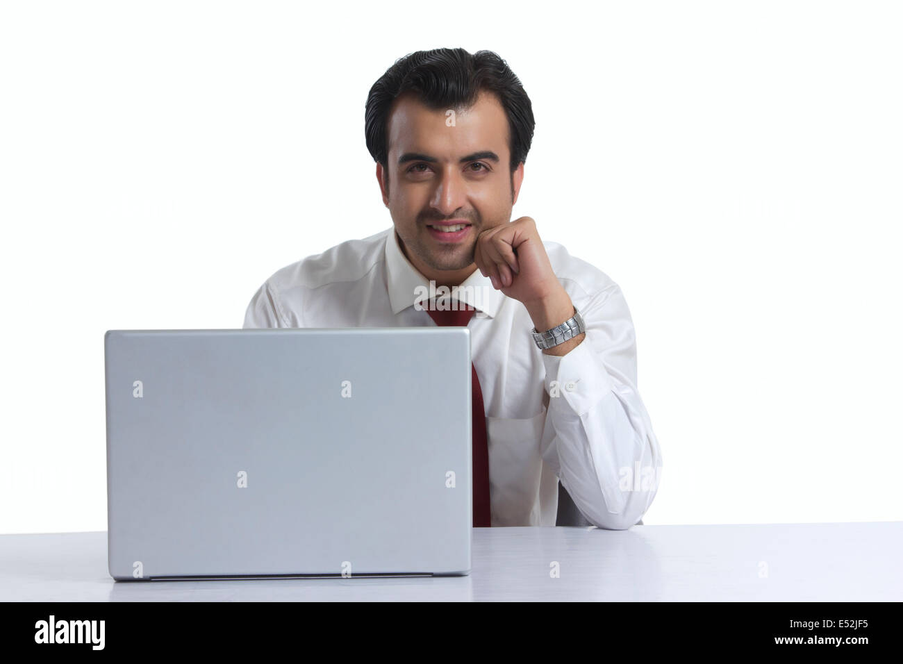 Portrait of smiling businessman with laptop at desk against white background Banque D'Images