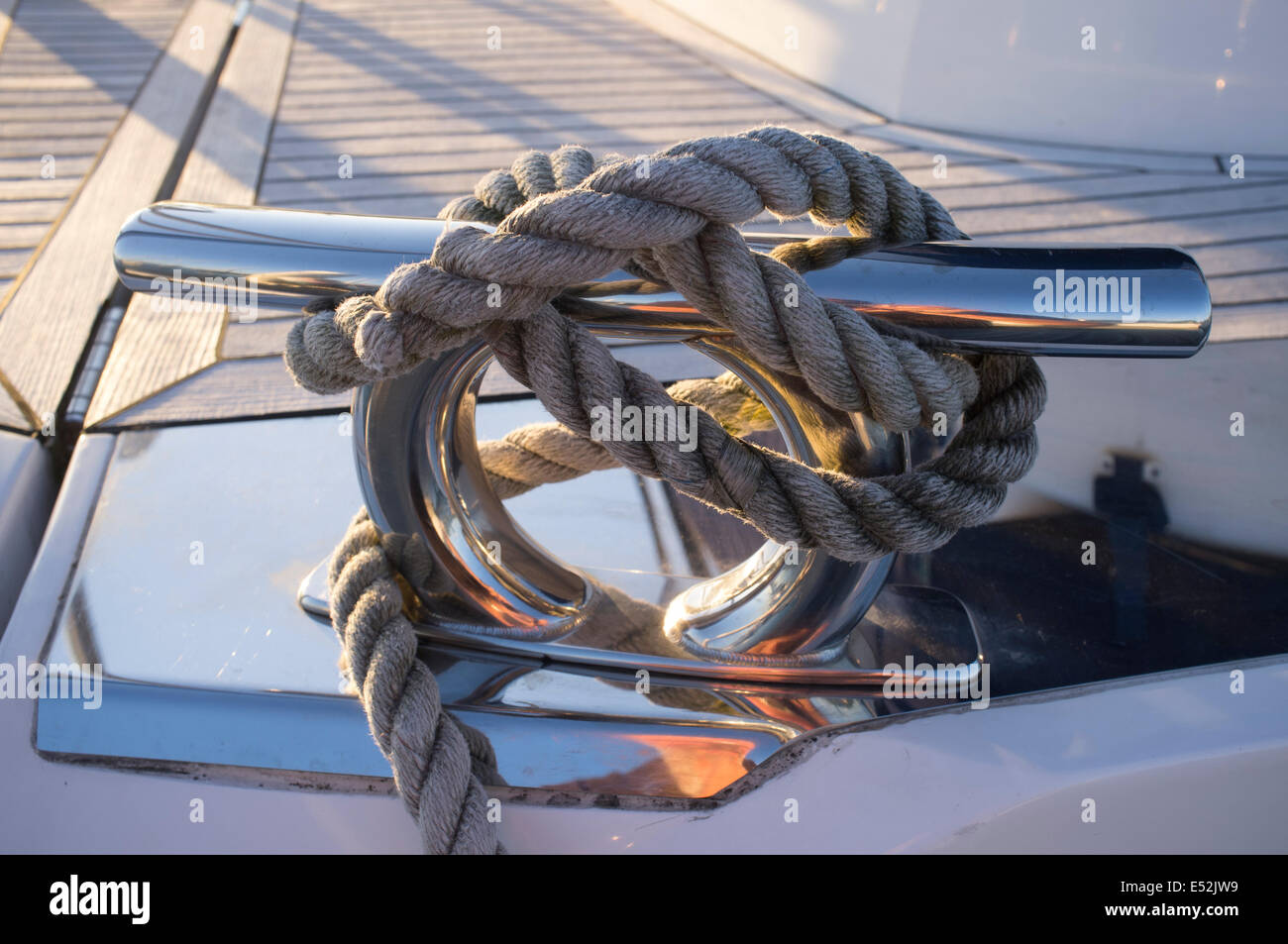 Corde enroulée autour d'un bateau en acier inoxydable avec taquet en teck Banque D'Images