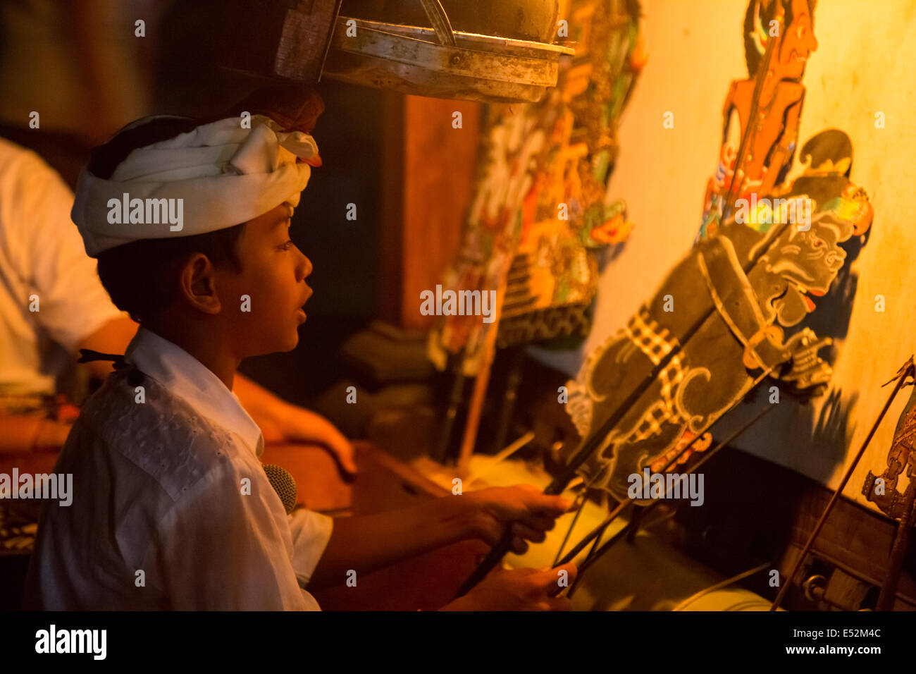 Denpasar, Bali, Indonésie. Jeune garçon récitant Histoire d'être exécutée par des ombres chinoises qu'il contrôle. Temple Pura Jagatnatha. Banque D'Images