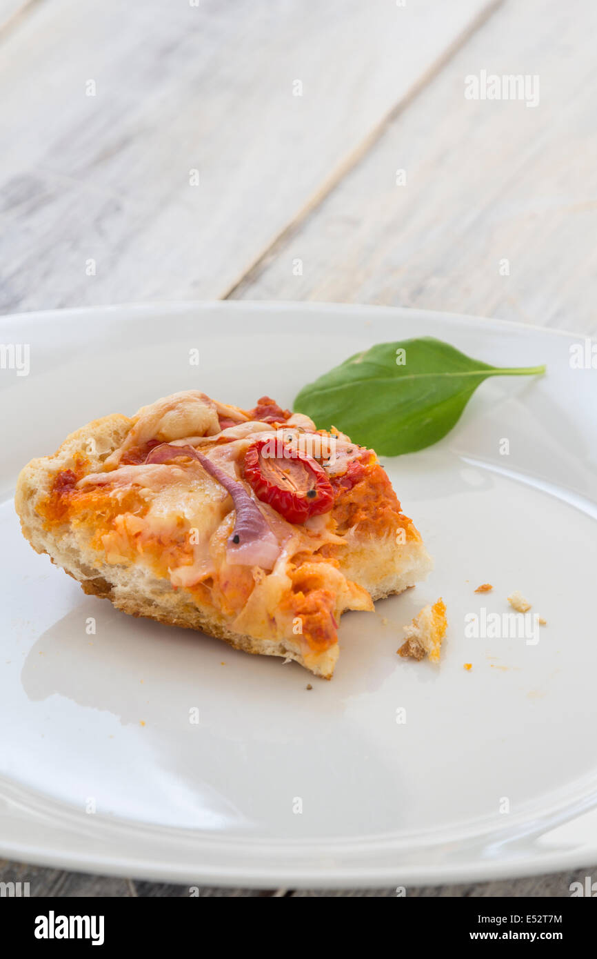 Les restes de pizza de la veille sur une plaque sur une table en bois rustique Banque D'Images