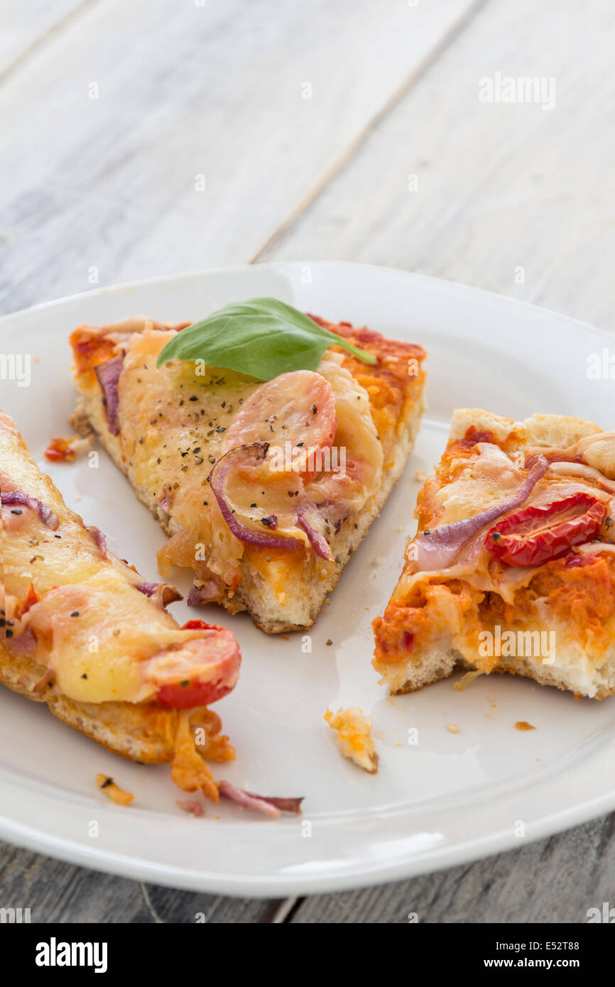 Les restes de pizza de la veille sur une plaque sur une table en bois rustique Banque D'Images
