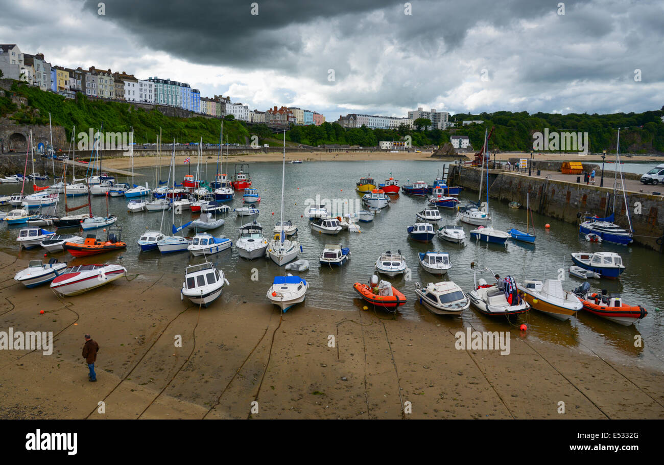 Un homme marche à travers l'exploitation des sables bitumineux au port de Tenby sous un ciel nuageux et maussade. Banque D'Images