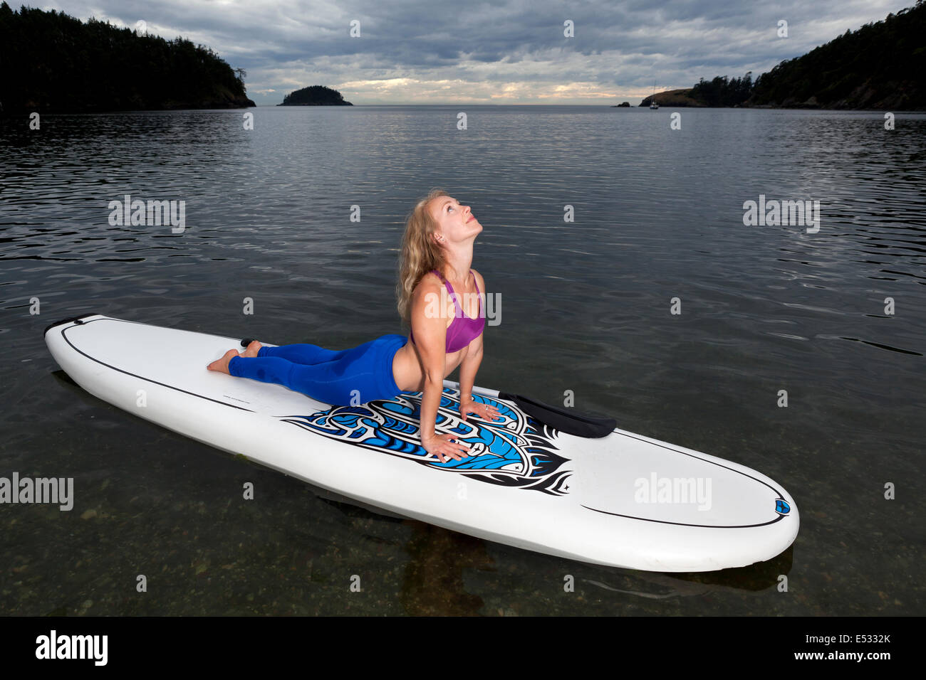 WASHINGTON - Professeur de Yoga Carly Hayden se réchauffer sur un, SUP (stand up paddle board), dans la région de Bowman Bay. Banque D'Images