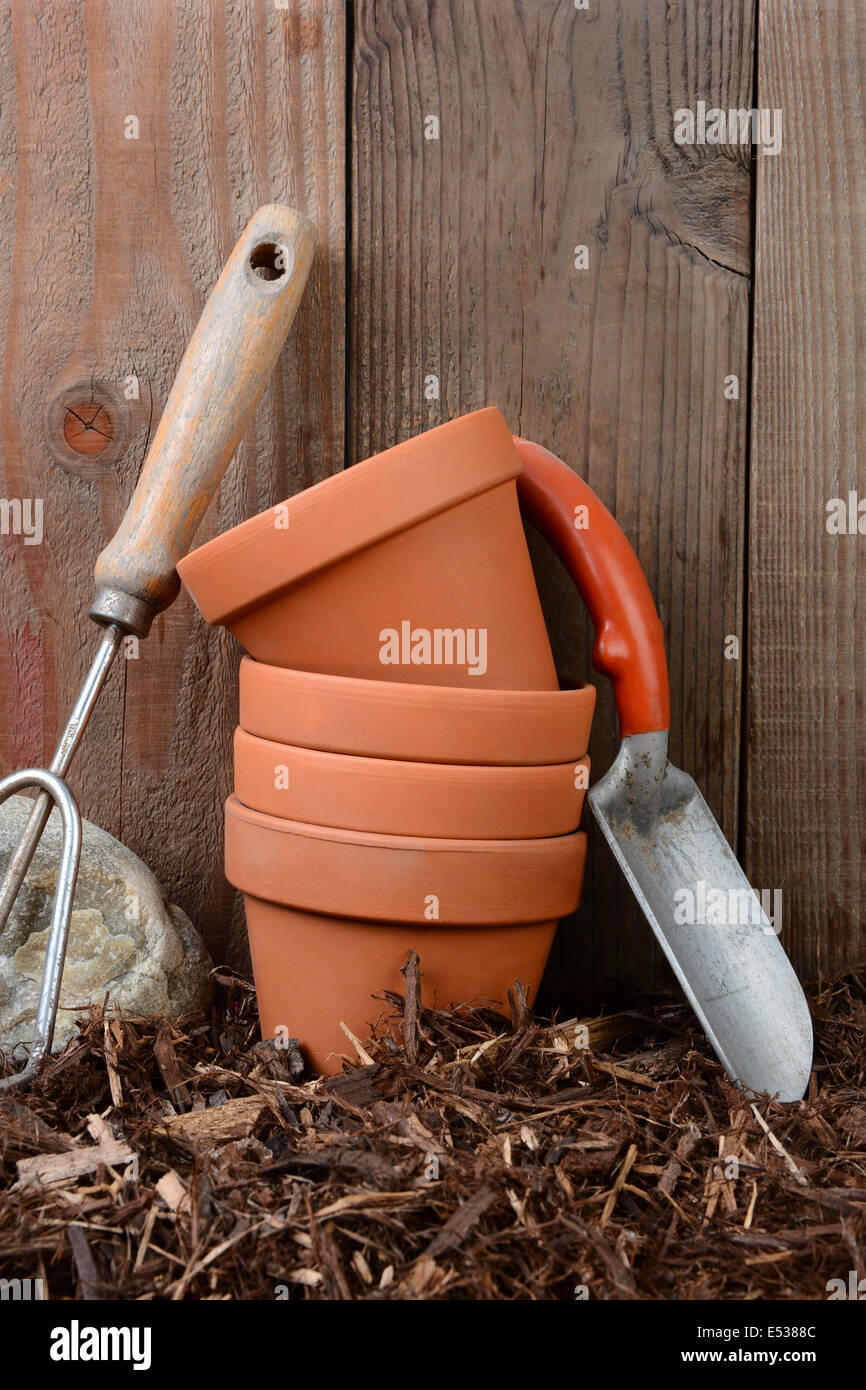 Libre d'outils de jardin et les pots de fleurs contre une clôture basse-cour en bois. Banque D'Images