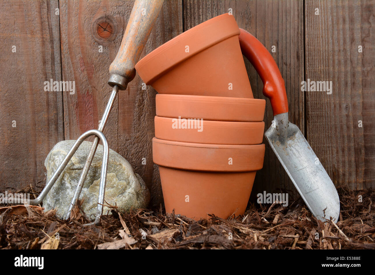 Libre d'outils de jardin et les pots de fleurs contre une clôture basse-cour en bois. Banque D'Images