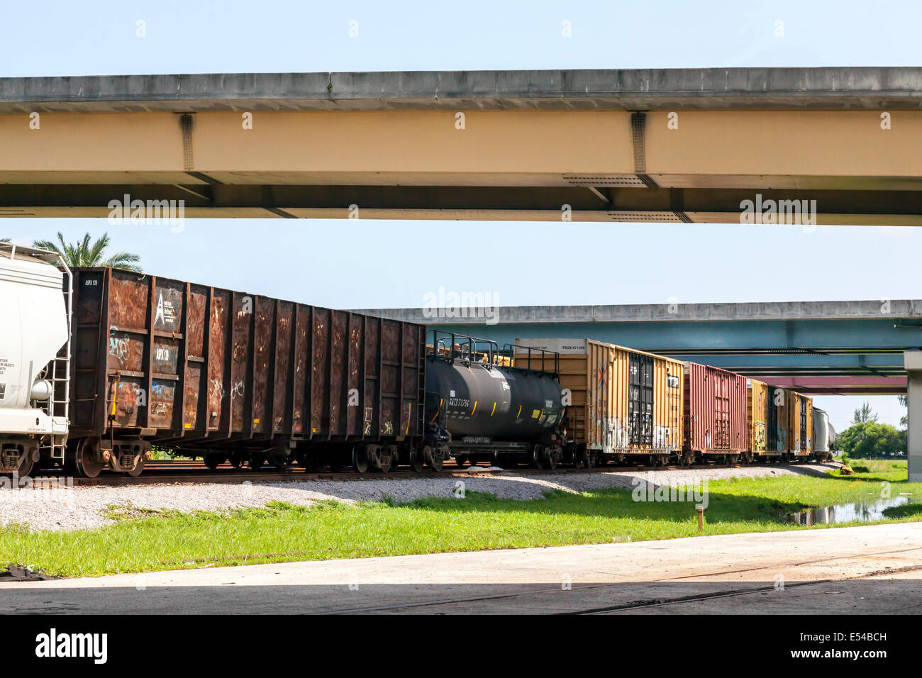 La rouille RR des wagons et du wagon-citerne assis sur une voie de chemin de fer sous l'autoroute de faisceau de viaducs. Banque D'Images