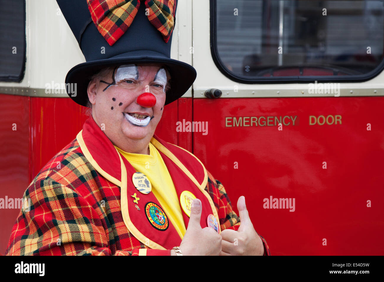 Clown professionnel de cirque, amusement, drôle, heureux, carnaval, fête, costume, humour, divertissement, célébration, visage rouge, bande dessinée, coloré, personnage, art, perruque. Un chapeau de tête et un costume de tartan drôles à Fleetwood, Lancashire. L'interprète Paul Davies est l'expression de la tristesse, de la surprise et de l'humour. Costume de clown coloré et chapeau art déco et animateur pour enfants au Festival of transport, Royaume-Uni Banque D'Images
