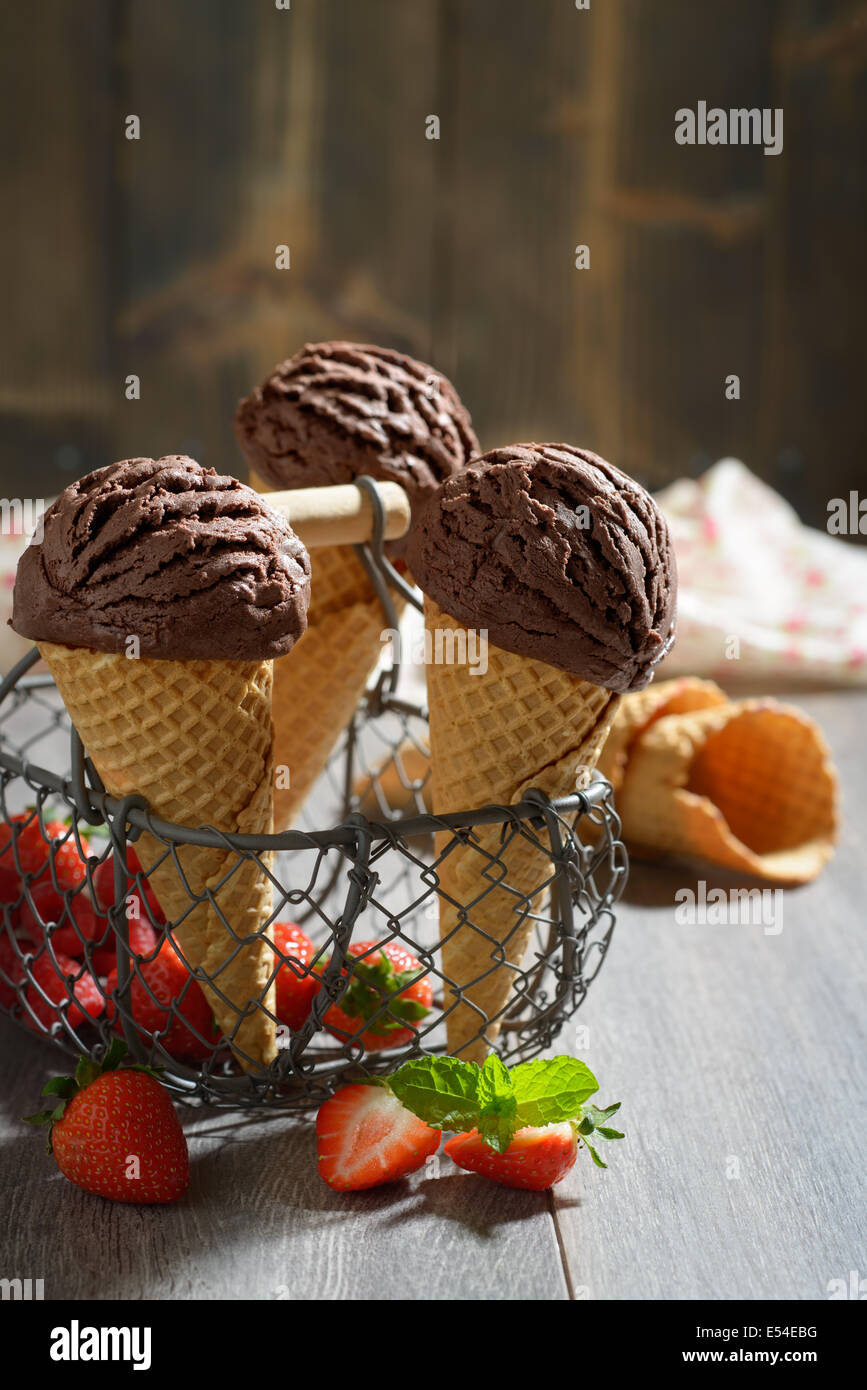 Glace au chocolat avec des fraises et crams cônes vides à l'arrière-plan Banque D'Images