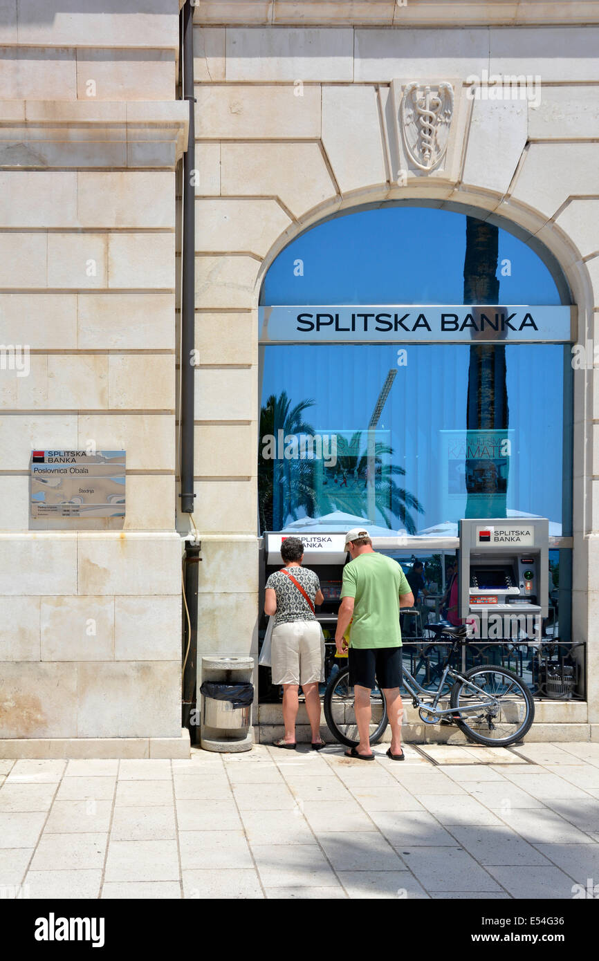 Couple standing par un distributeur de billets à l'extérieur d'une succursale de la Splitska Banka (propriété de la Société Générale) dans le centre-ville de Split Banque D'Images