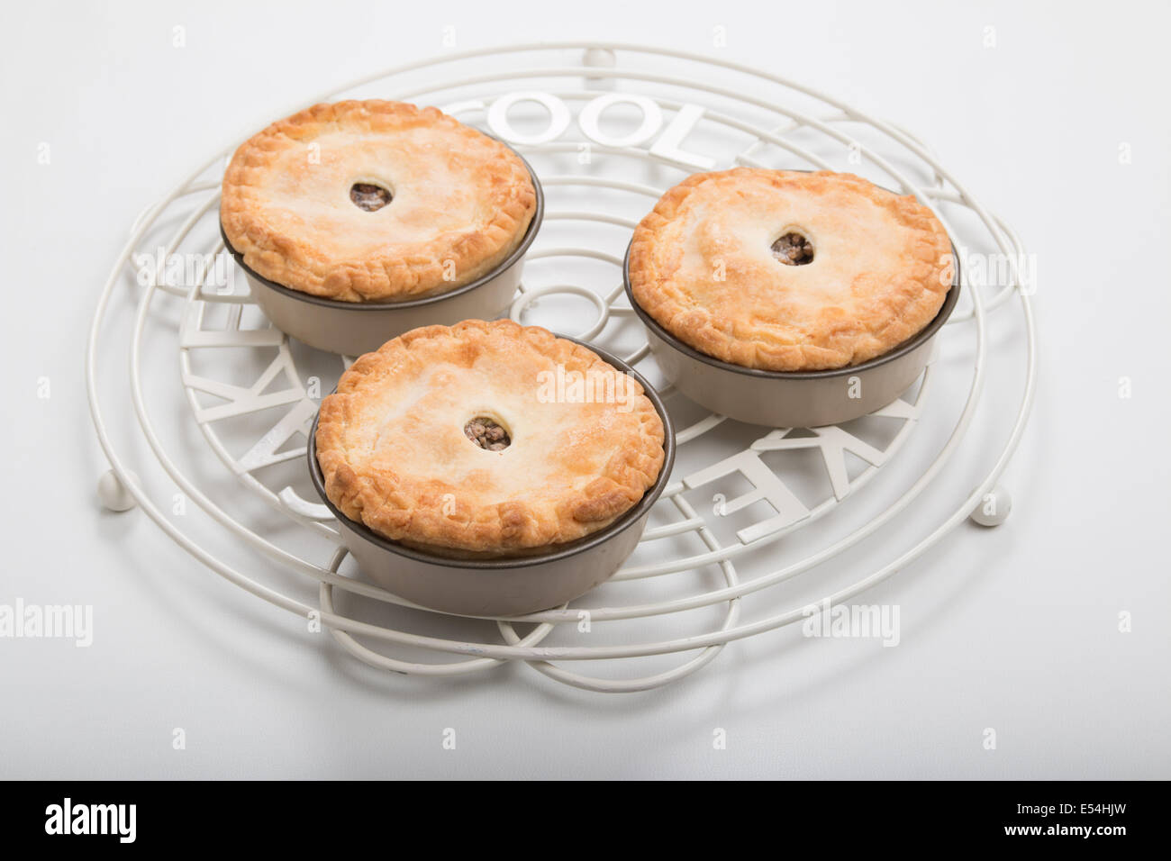 3 petites tourtières en moules sur une grille ronde sur un fond pâle tartes individuelles adapté pour un pique-nique (11 de 20 ) Banque D'Images