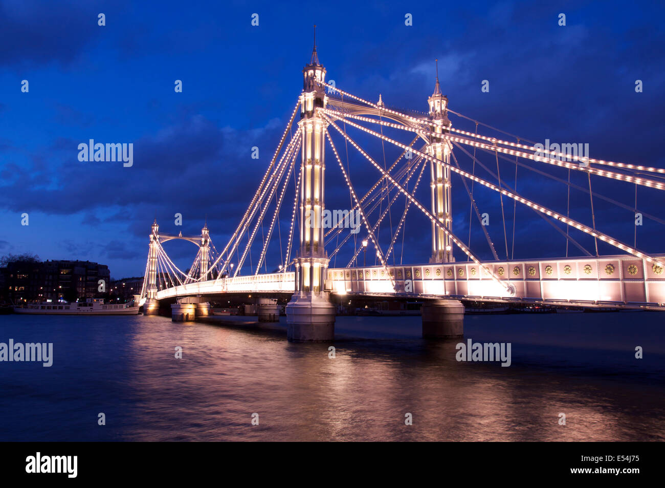 La lumineuse splendeur victorienne d'Albert Bridge, allumé à la tombée de la nuit, en traversant la Tamise entre Battersea et Chelsea. Londres, Angleterre, Royaume-Uni. Banque D'Images