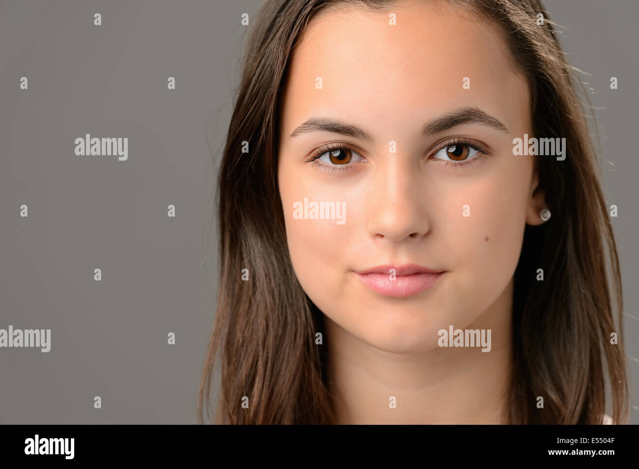 Teenage girl beauté visage cosmetics brunette close-up sur gris Banque D'Images