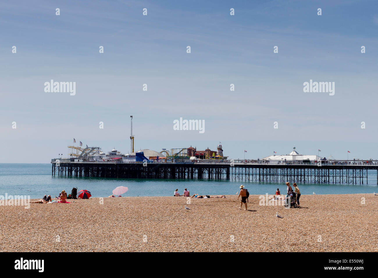 Les personnes bénéficiant du soleil sur la plage de Brighton et de la jetée, East Sussex, England, UK Banque D'Images