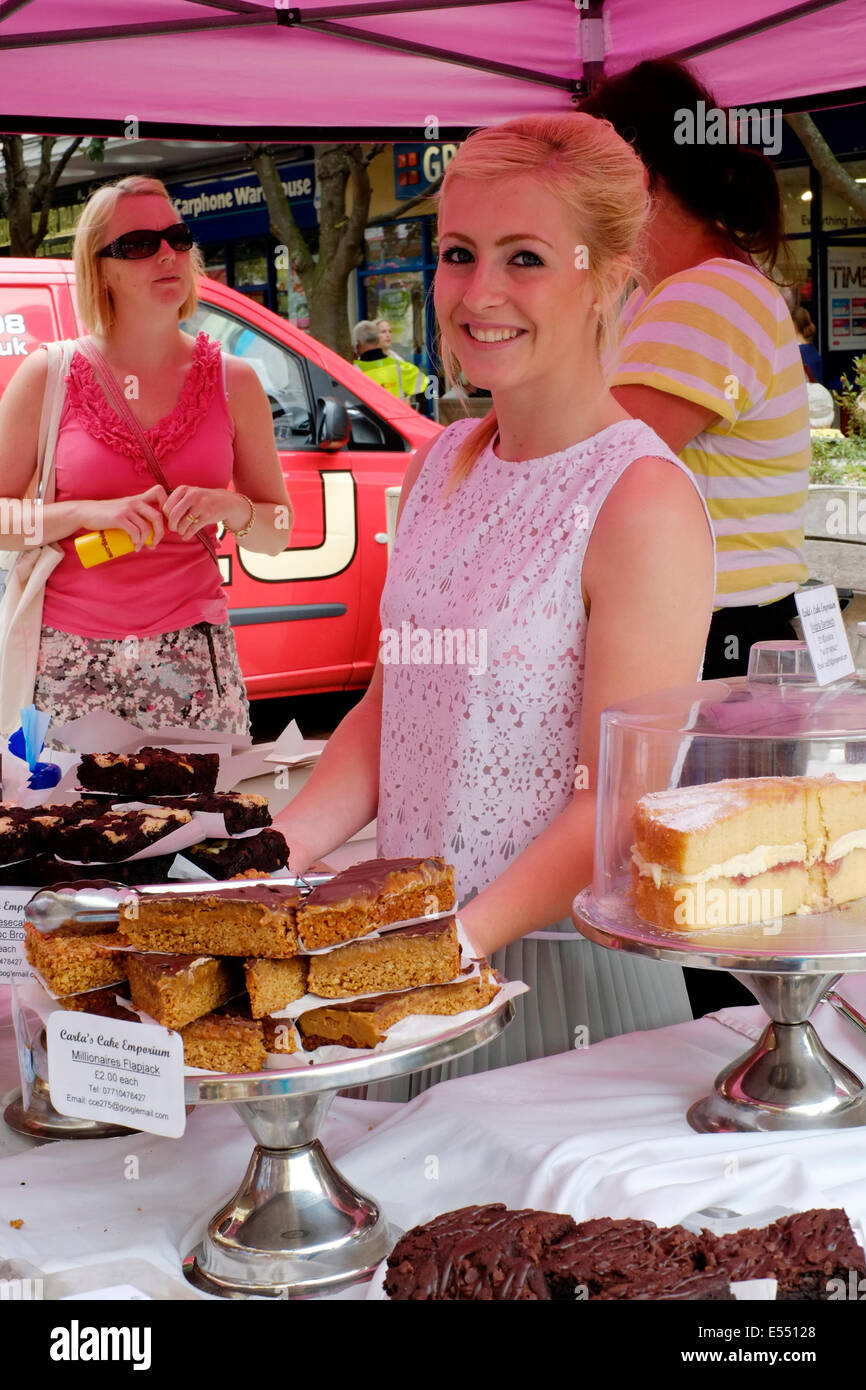 Souriante jeune femme vendant des gâteaux à partir d'un stand au salon de l'alimentation de Southsea festival 2014 england uk Banque D'Images