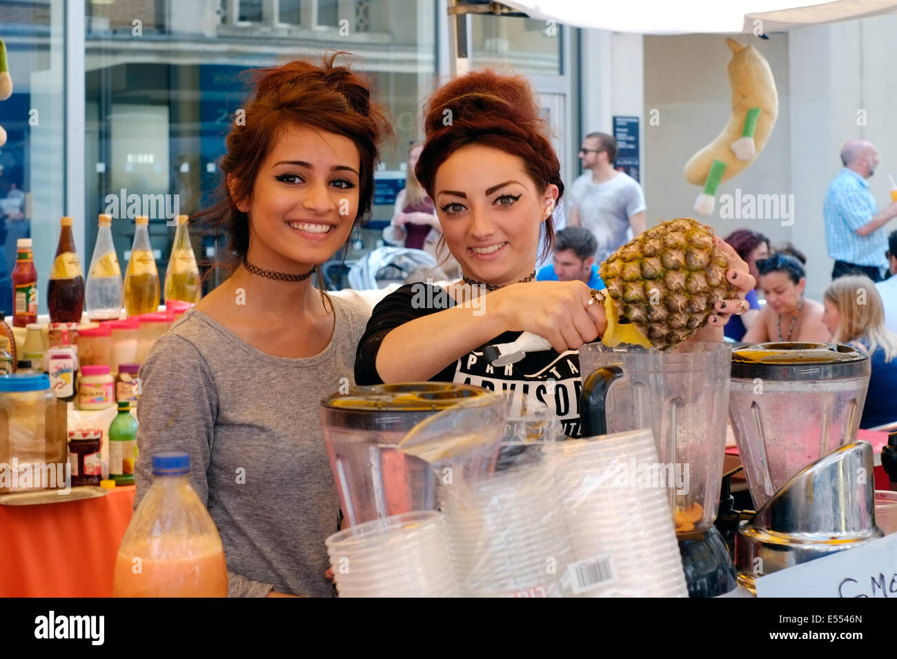 Deux jolies jeunes filles souriant smoothies aux fruits mélange à la foire alimentaire de Southsea festival 2014 england uk Banque D'Images