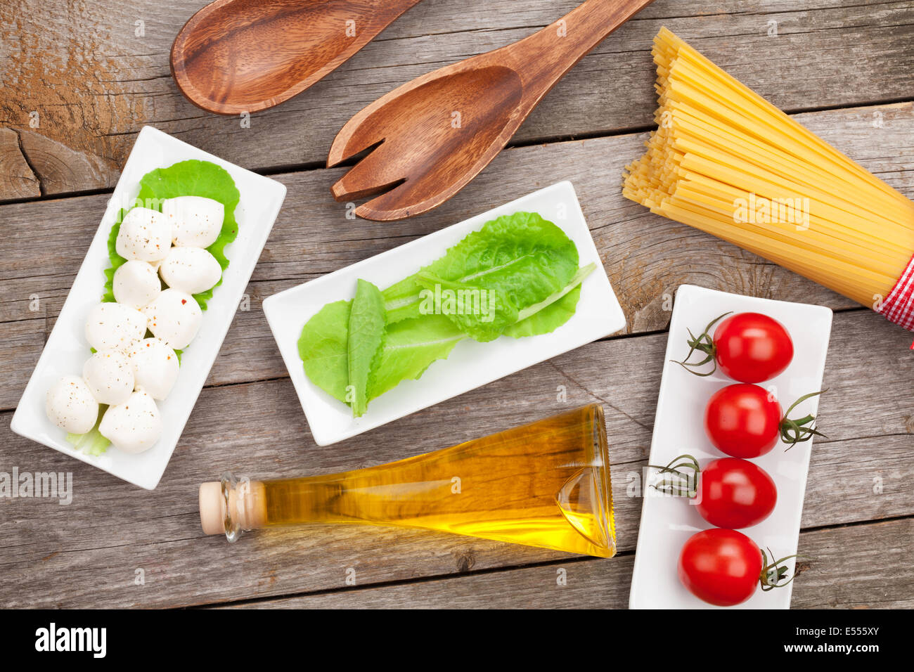 Tomates, mozzarella, pâtes et salade verte feuilles sur fond de table en bois Banque D'Images