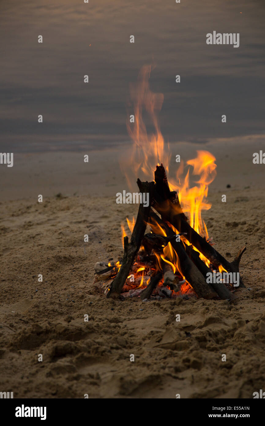Feu de joie sur la plage de sable après le coucher du soleil Banque D'Images