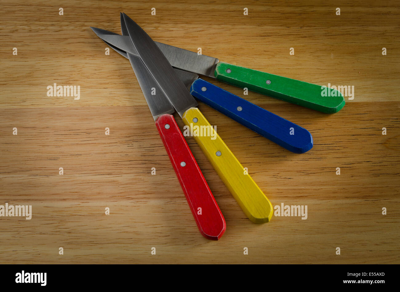 Couteaux sur bois, rouge, jaune, bleu, vert Banque D'Images
