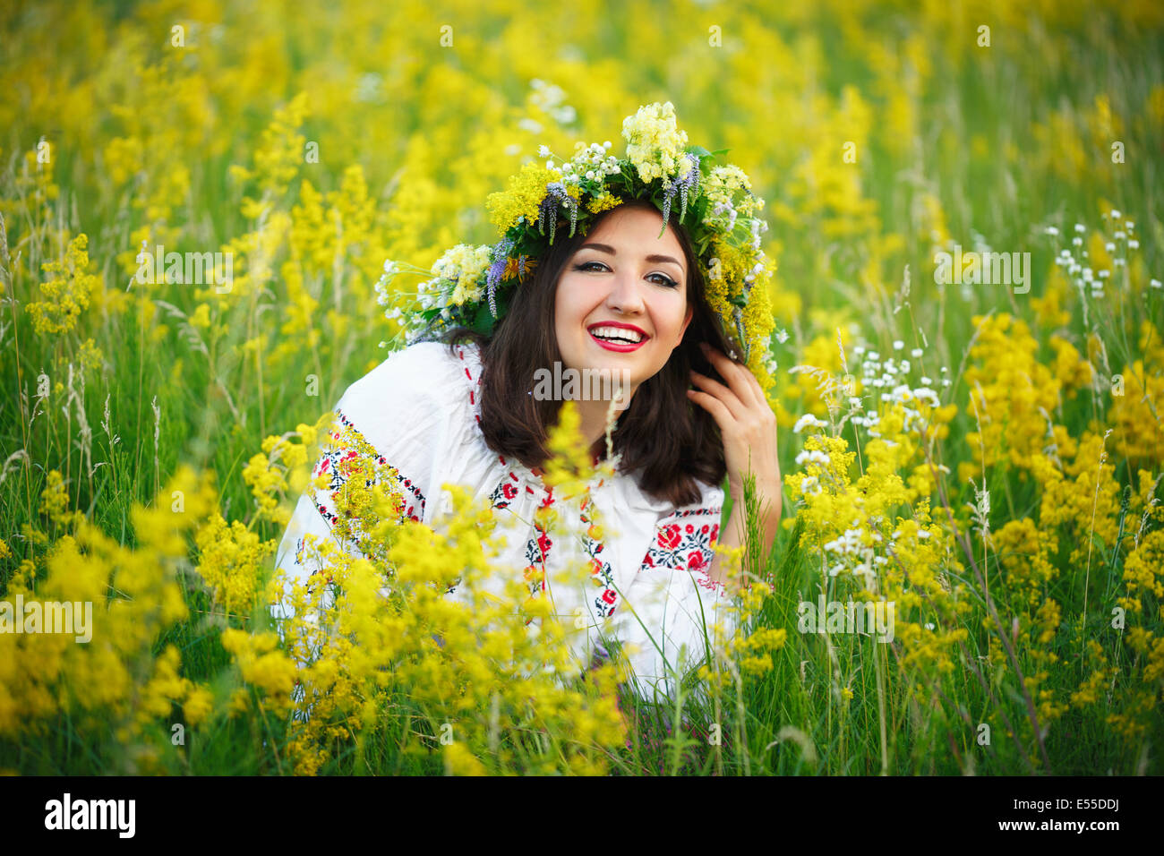 Young beautiful smiling girl en costume ukrainien avec une couronne sur sa tête dans un pré Banque D'Images