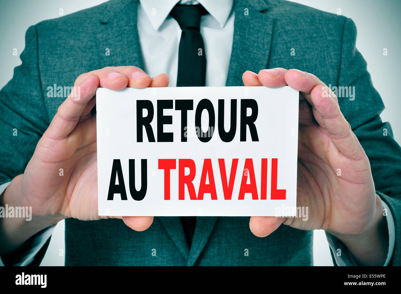 Businessman avec une pancarte portant le texte retour au travail, retour à travailler en français, écrit en c Banque D'Images