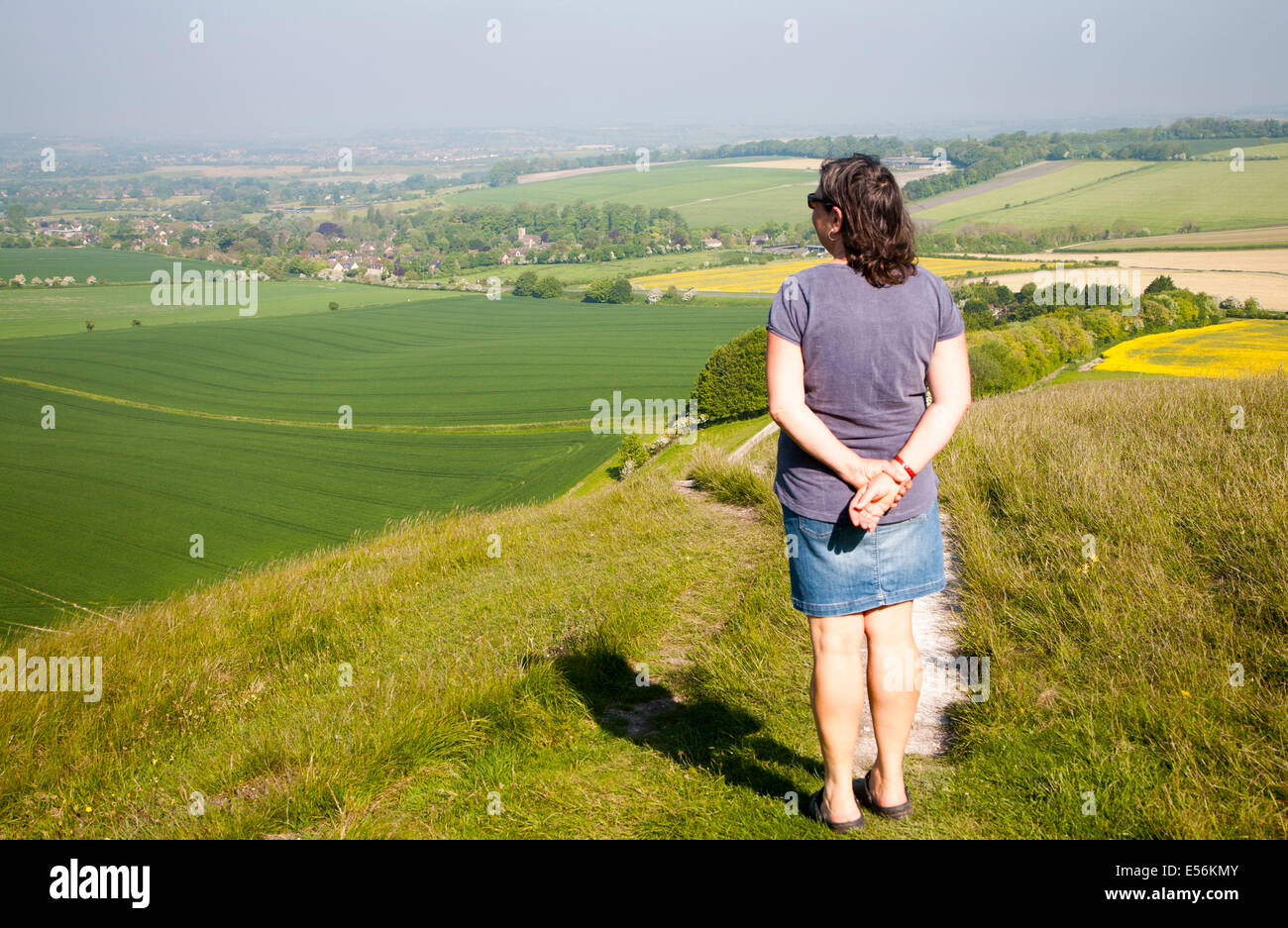 Femme debout sur la pente raide d'escarpe craie Winfield, Wiltshire, Angleterre à la recherche vers le village de Winfield Banque D'Images