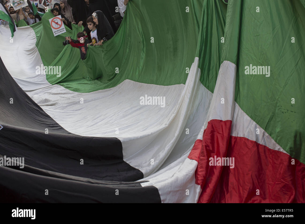 Téhéran, Iran. 22 juillet, 2014. Les enfants iraniens tenir un coin d'un drapeau palestinien au cours d'une protestation contre l'action militaire d'Israël contre Gaza, en face de la section des intérêts de la République arabe d'Égypte dans le nord de Téhéran. L'Egypte a appelé les manifestants à rouvrir la frontière de Rafah pour le transfert des soins médicaux à Gaza. Morteza Nikoubazl/ZUMAPRESS : Morteza Nikoubazl Crédit/ZUMA/Alamy Fil Live News Banque D'Images