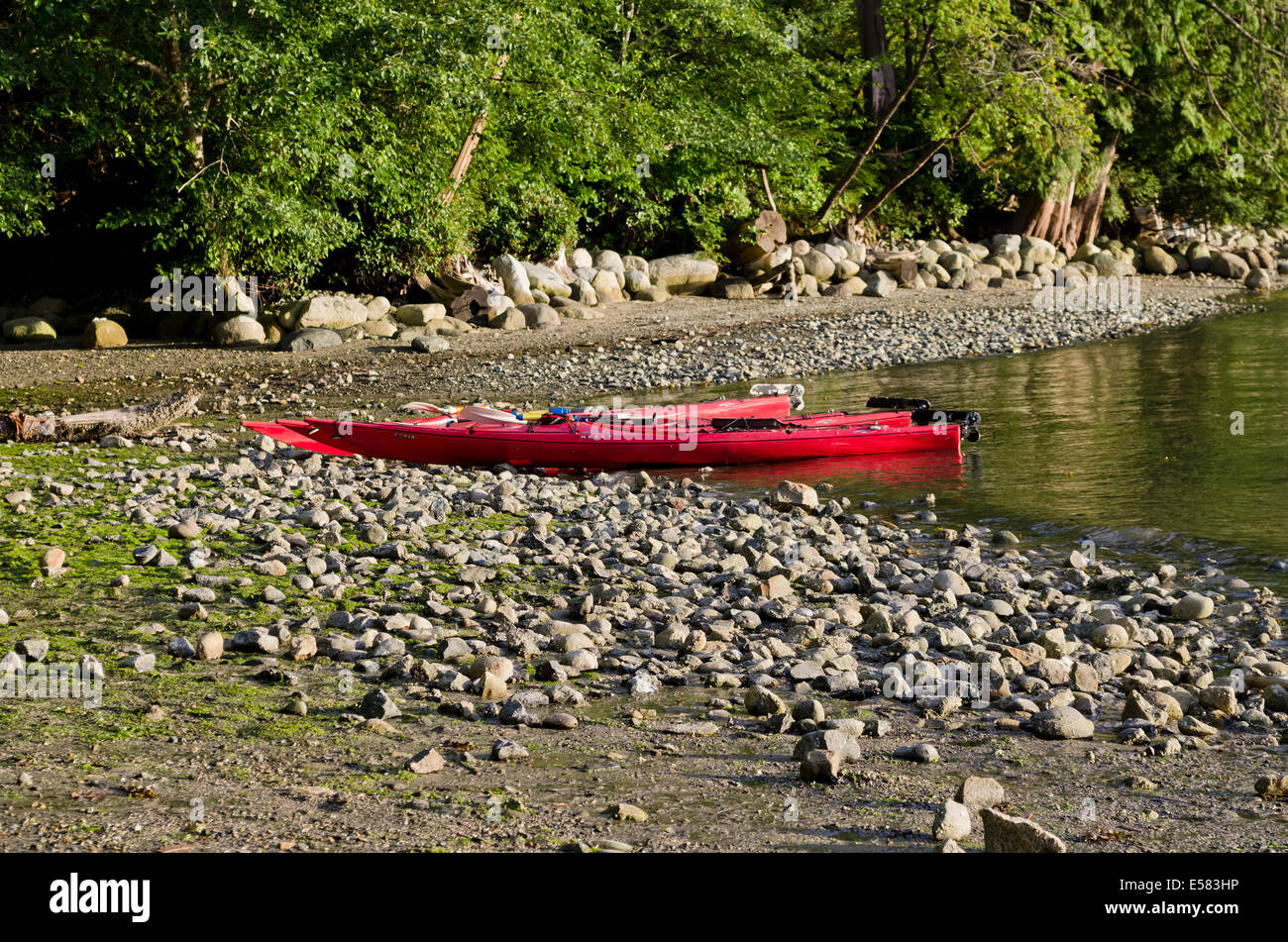 Deux kayaks rouges assis sur la côte rocheuse par l'eau et de la forêt du parc régional de Belcarra dans le Grand Vancouver, BC, Canada Banque D'Images