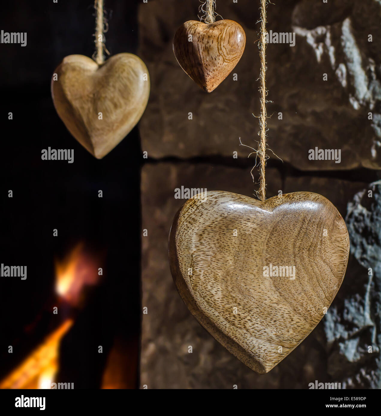 Coeurs en bois accroché contre une vieille cheminée en pierre Banque D'Images