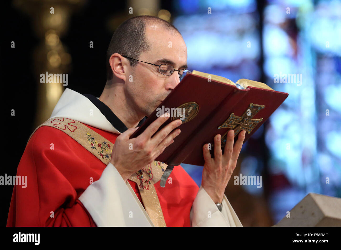 Prêtre catholique, embrassant la bible au cours d'un service dans une église catholique de Paris, France Banque D'Images