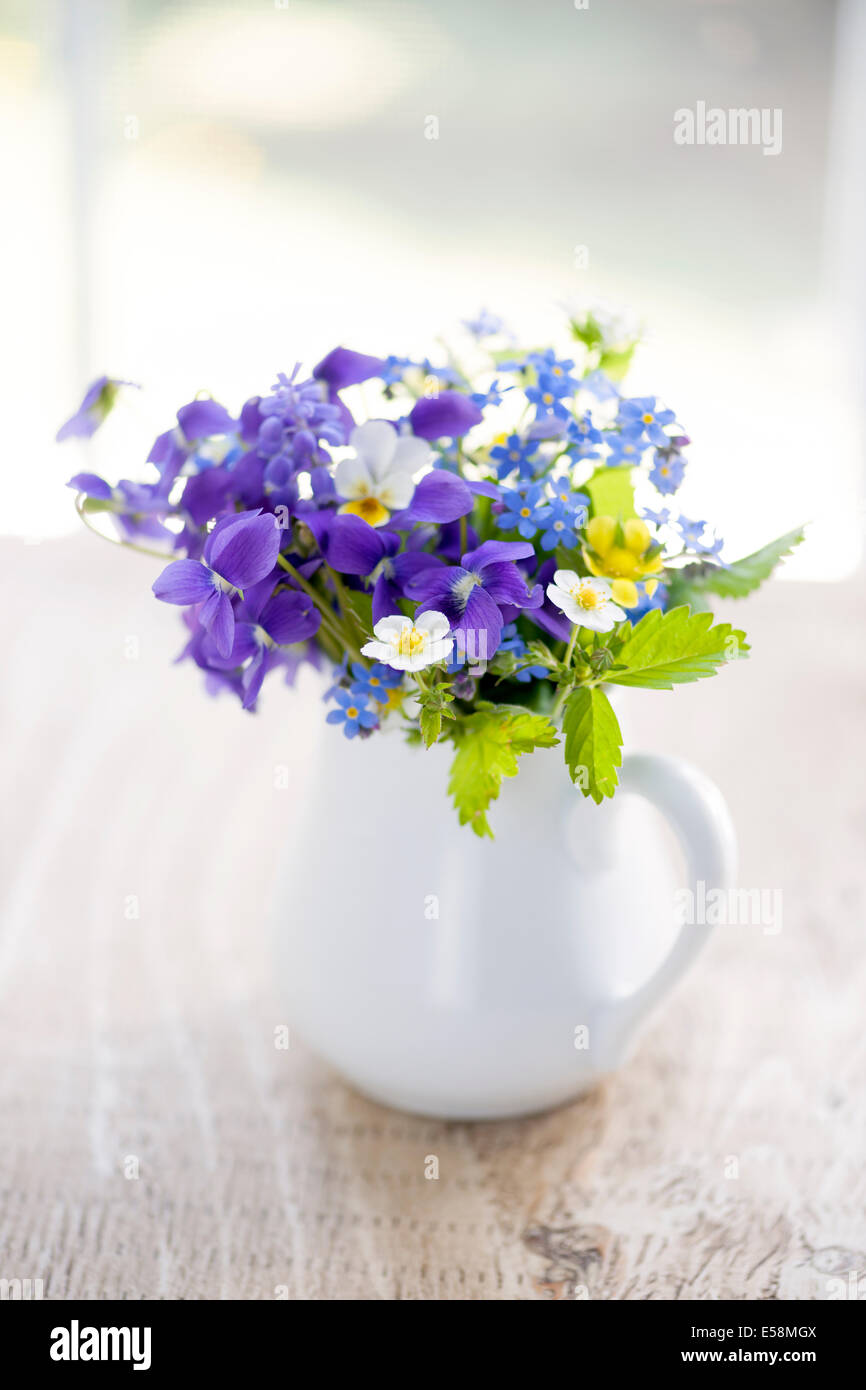 Bouquet de fleurs sauvages en vase blanc sur la table en bois rustique près de fenêtre, lumière naturelle Banque D'Images
