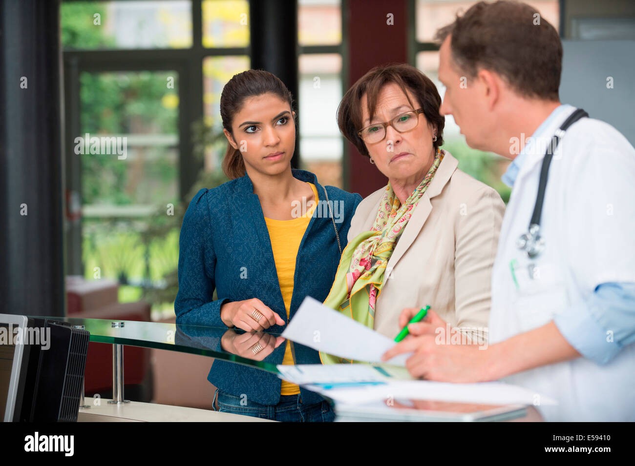 Médecin homme discuter avec les patients de l'hôpital rapport au bureau de réception Banque D'Images