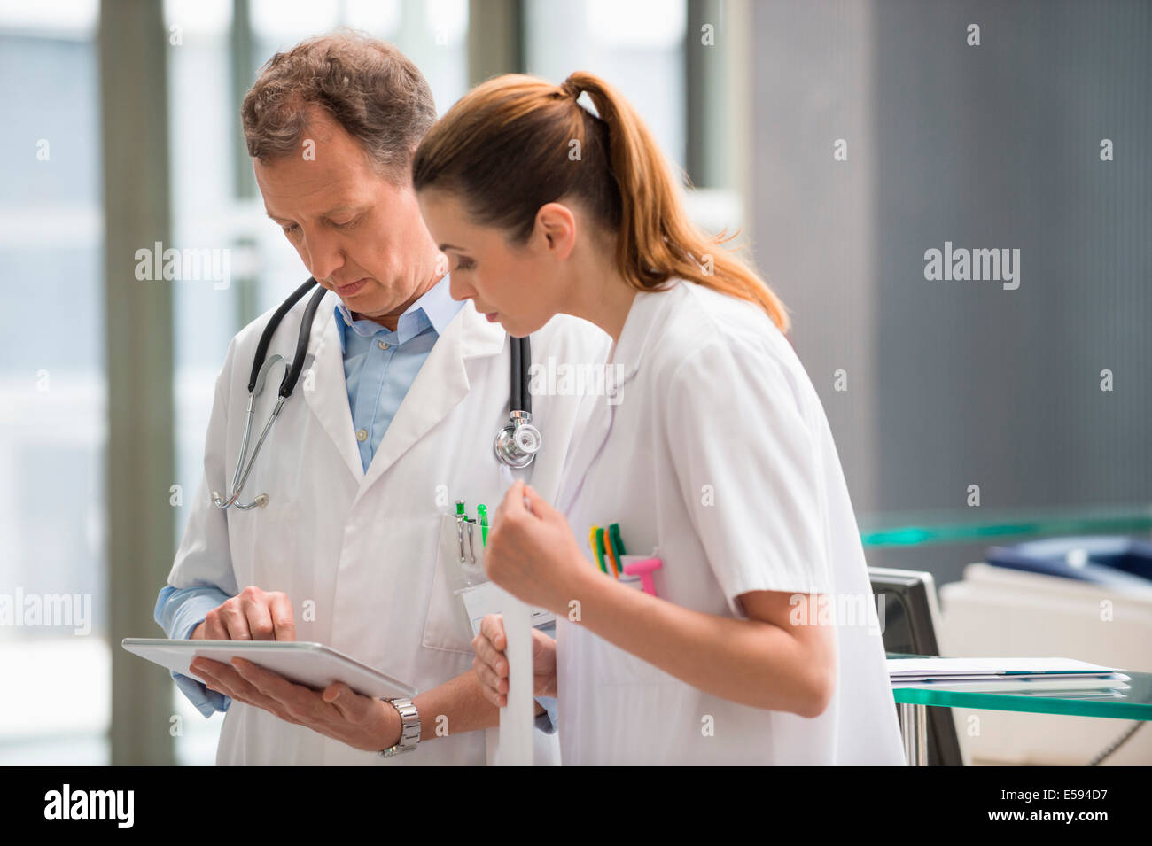 Deux médecins l'analyse de rapport médical sur digital tablet in hospital Banque D'Images
