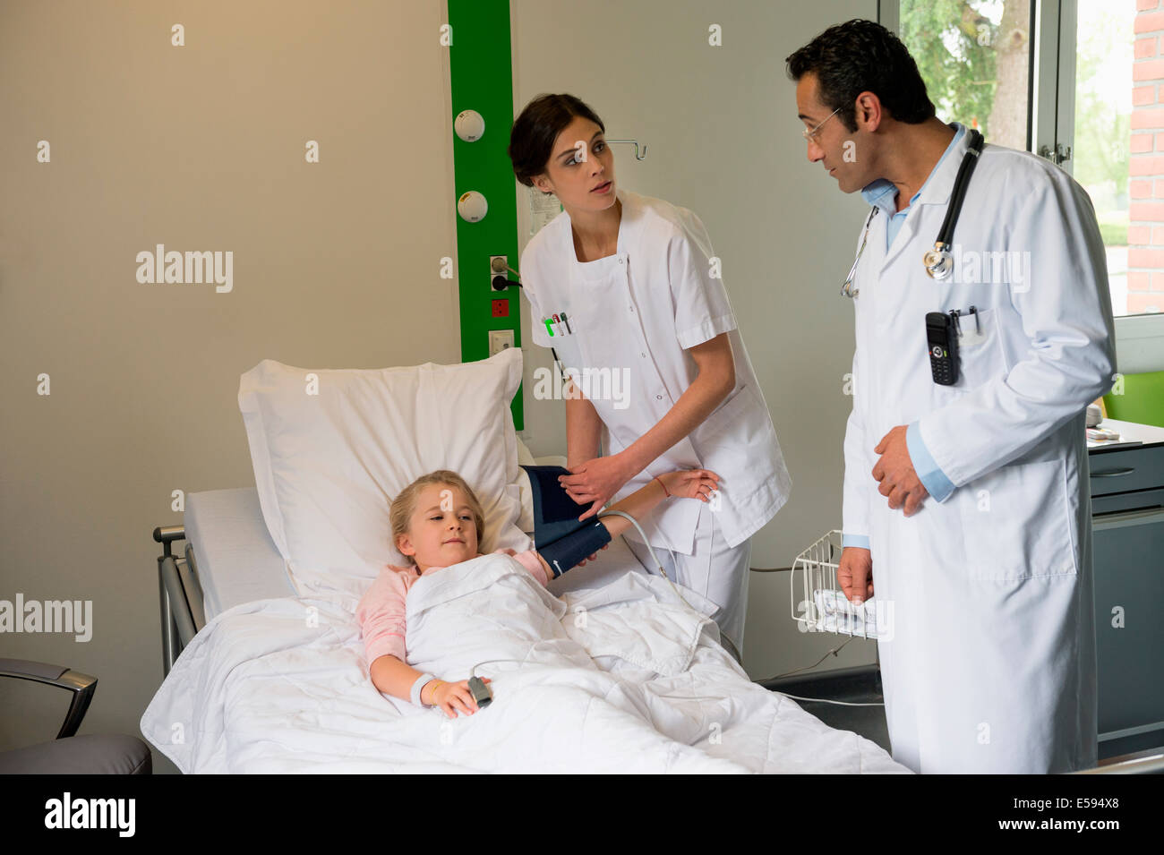 Auxiliaires médicaux à une jeune fille l'examen patient in hospital bed Banque D'Images