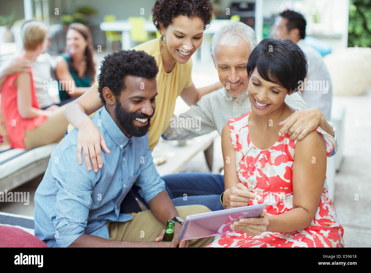 Des amis à l'aide de digital tablet at party Banque D'Images