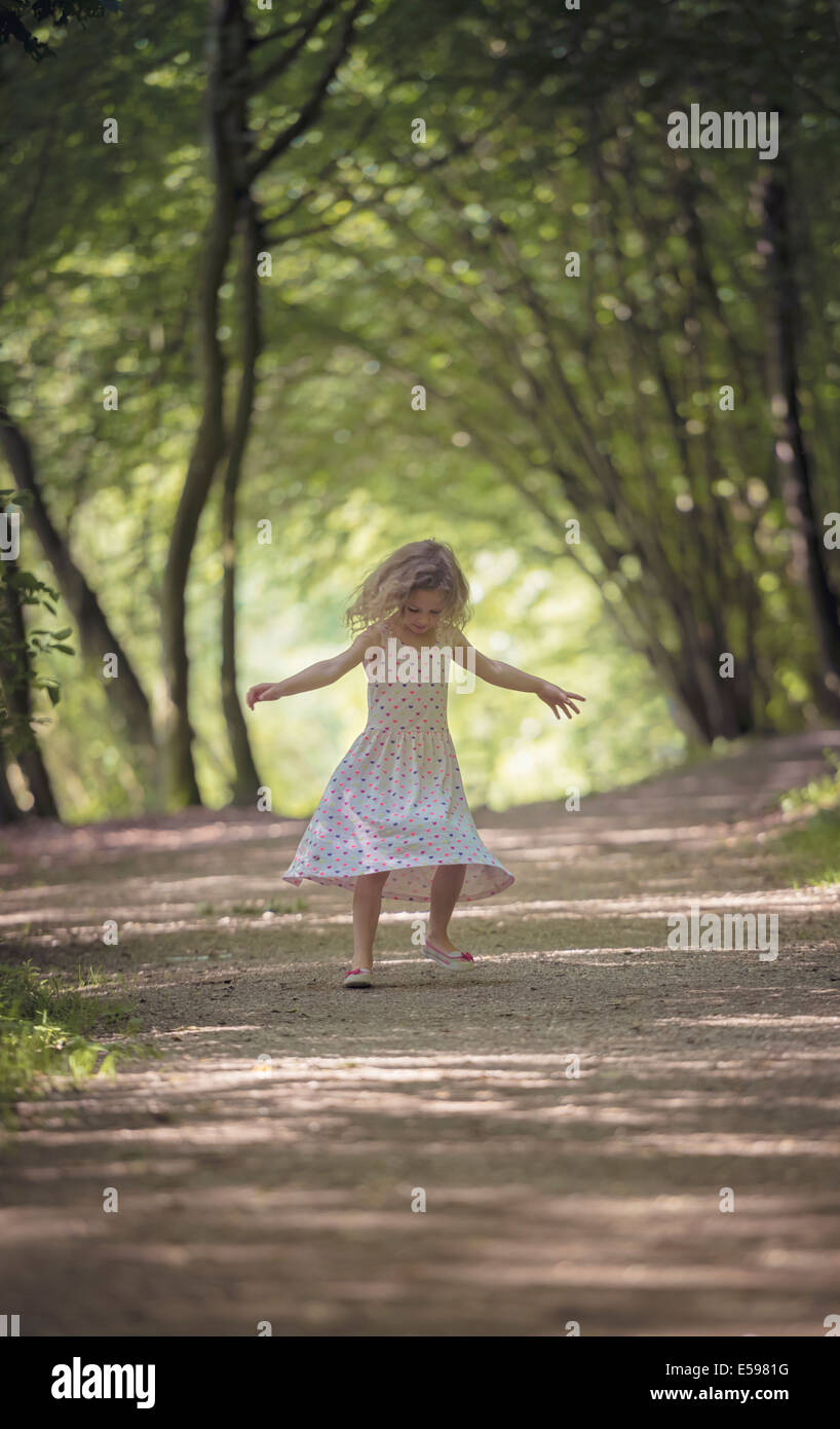 Petite fille dansant sur piste en forêt Banque D'Images