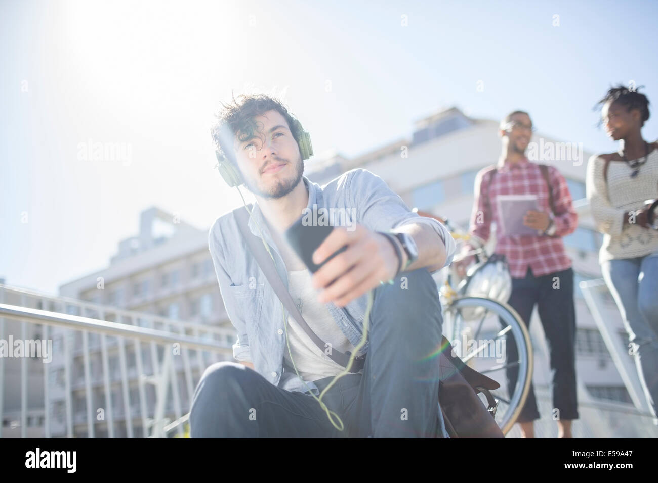 Man listening to headphones on city street Banque D'Images