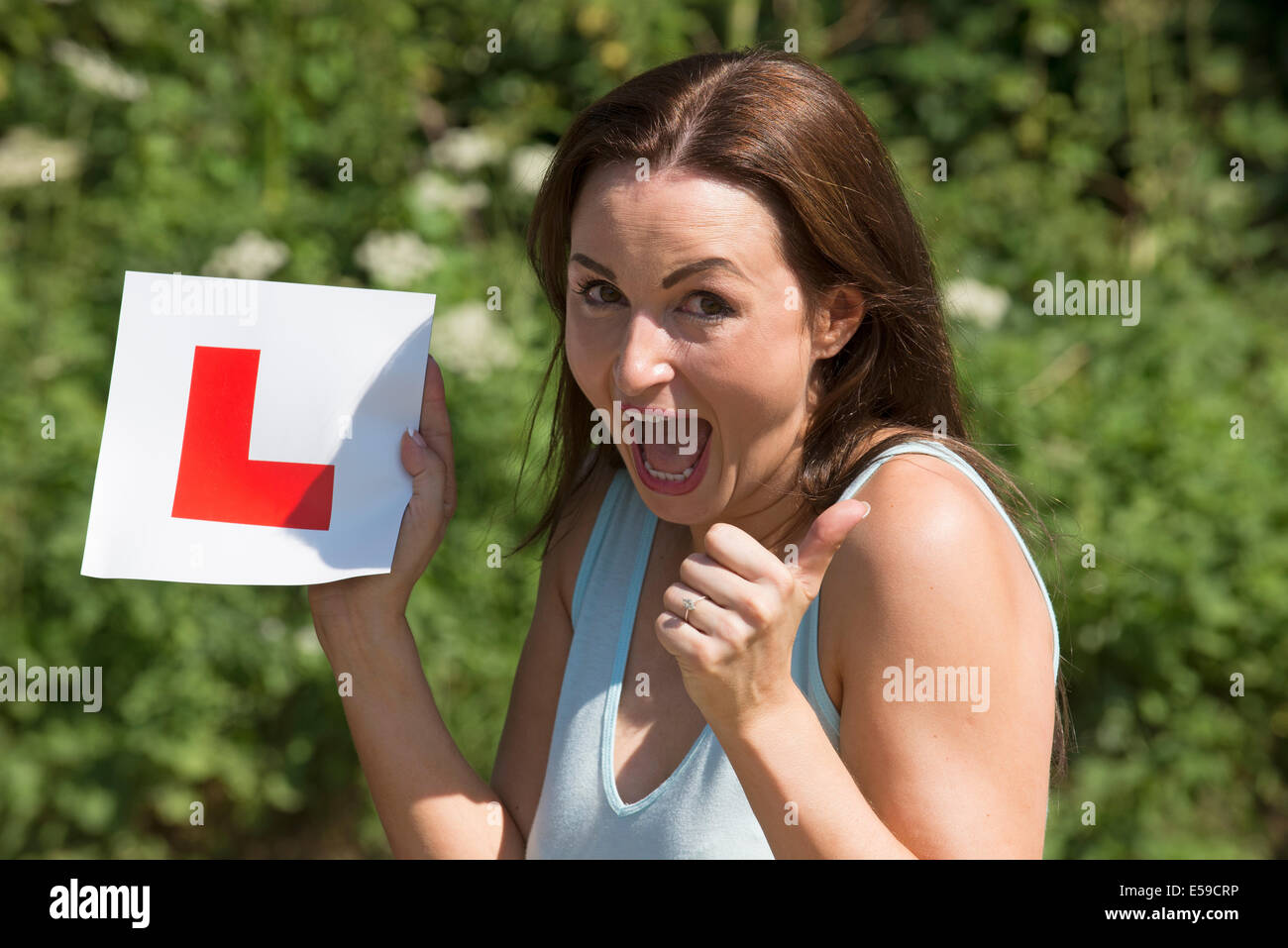 Portrait d'un pilote jubilant avec plaque après avoir passé l'examen de conduite. Donner un coup de pouce sign Banque D'Images