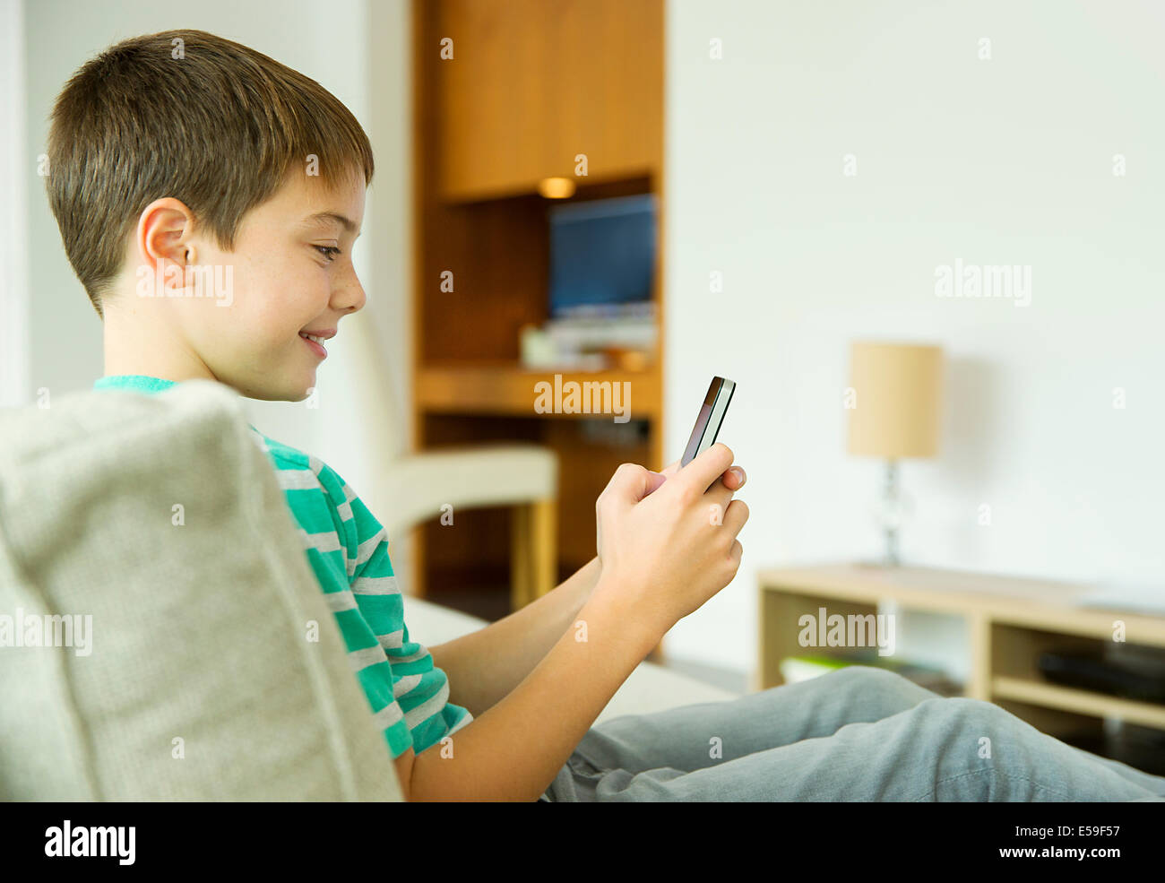 Boy using cell phone in living room Banque D'Images