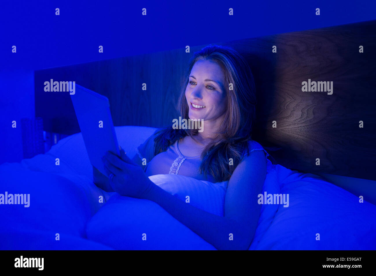 Woman using digital tablet in bed Banque D'Images