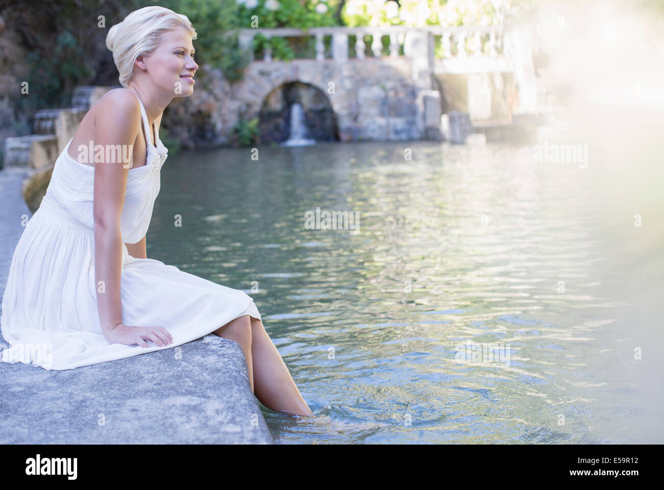 Woman dangling pieds dans la piscine Banque D'Images